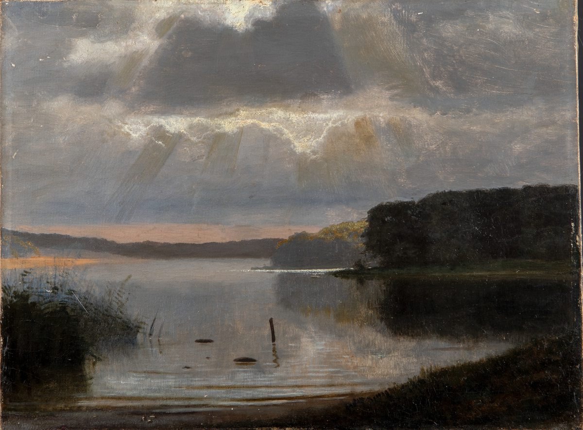 Maleri. Liggende profil. Ukjent kunstner, men rammen er signert Vestergaard. Motiv av vann i forgrunnen, i bakgrunnen skyer med solstråler. Maleriet har gullbelagt ramme av tre.