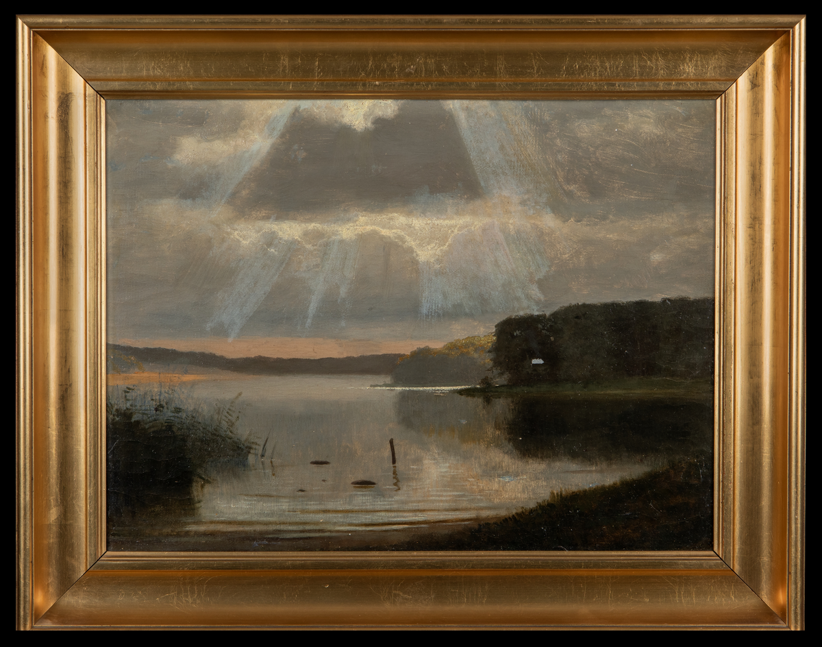 Maleri. Liggende profil. Ukjent kunstner, men rammen er signert Vestergaard. Motiv av vann i forgrunnen, i bakgrunnen skyer med solstråler. Maleriet har gullbelagt ramme av tre.