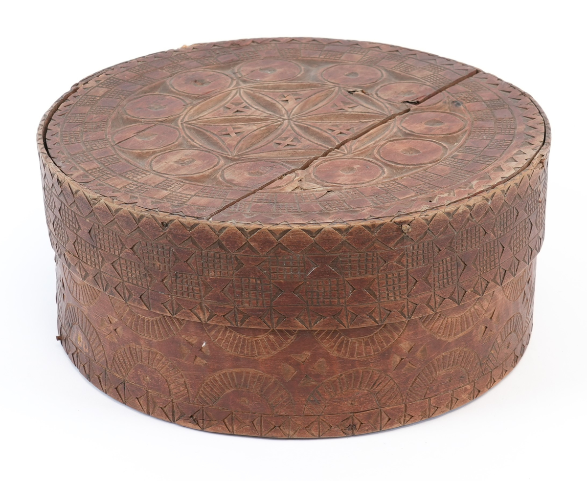 Karveskurd over heile øskja. På toppen av lokket ei sentral seksbladrose innskriven i ein sekskant med konkave sider, alt i ein sirkel. Mellom roseblader utskorne krysskors. Rundt rosa ei brei stripe med utskorne sirklar. Rundt dei, eit maskulint muruspjeld og sikksakk langs kanten. På sideveggen av lokket dobbel sikksakk langs kanten og muruspjeld med vekslende felt (rutenett og ståande timeglass symbol). På sideveggen av behaldaren, langs kantane stripar med ståande timeglass symbol. Mellom dei halvsirklar og krysskors.