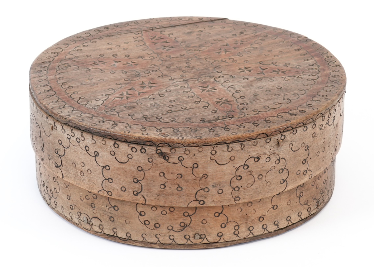 Svidekor over heile øskja. På toppen av lokket ei stor, sentral seksbladrose innskriven i ein sirkel med to melteserkors på kvert roseblad. Rosa og sirkelen måla raud. Langs sida sirklar av bogar og ringar. Alle linjene i ornamentet har form av svidde, små bogar og ringar.