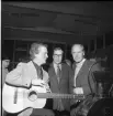 Tre män varav en med gitarr.
