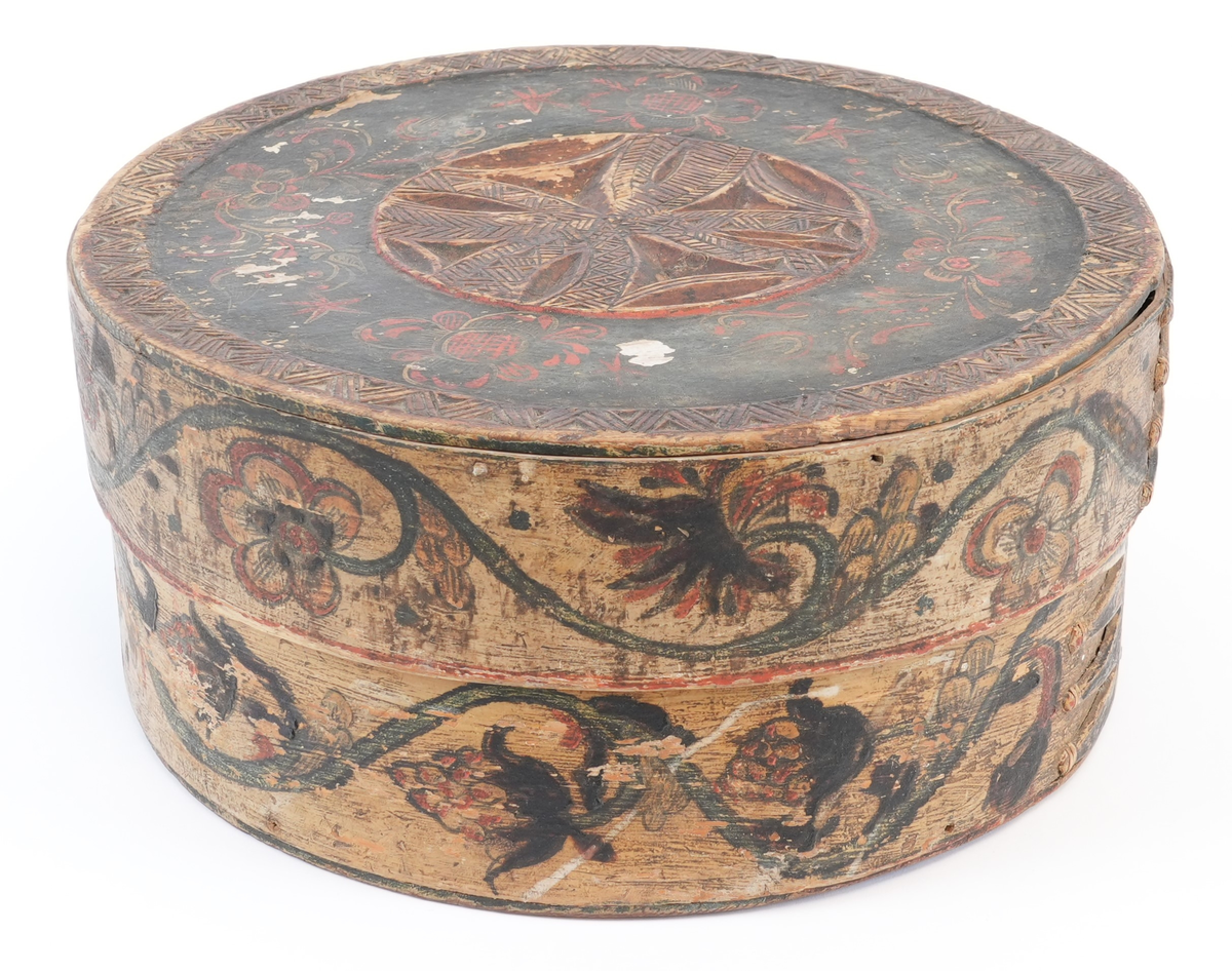 På toppen av lokket karveskurd: i midten utskore eit stort, sentralt buekors med rutenett og sikksakk inni; langs kanten utskoren sikksakk. Mellom dei, på mørkegrøn bakgrunn måla raude og gule blomstrar og slynger. På sideveggen, på kvit bakgrunn måla grøne rankar med raude og gule blomstrar og drueklasar. Innvendig restar av blå målingslaget: på lokket synleg blomsterform, på botnen s-ar.