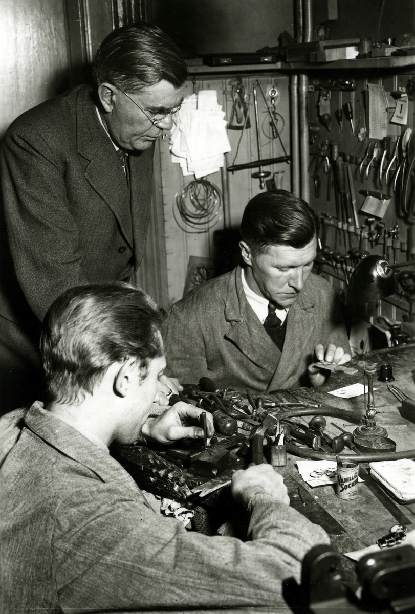 Guldsmed Gunnar Svensson, Kalmar, mannen med ryggen är Nils Johansson, sedermera "Guld - Nils"  med affär på Larmgatan.
1930 - talets slut.