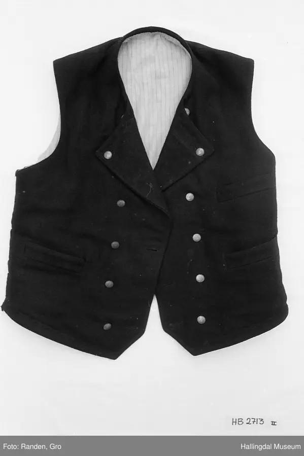 Mannsbunad fra Hallingdal, trøye, langbukse og vest. Trøye i svart vadmål. Svart fløyelskrage. Stikningar i rygg, front, lommer og erme. Ei brystlomme og to lommer, samt ei innerlomme. Stripa for i raudt, gult, grønt og blått. Blåstripa for i ermene. 10 sølvknappar framme laga av gamle myntar. Samt tre i kvart erme. Vest og lang bukse.
