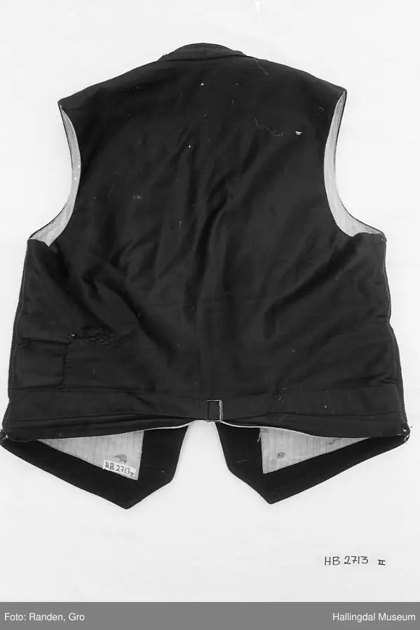 Mannsbunad fra Hallingdal, trøye, langbukse og vest. Trøye i svart vadmål. Svart fløyelskrage. Stikningar i rygg, front, lommer og erme. Ei brystlomme og to lommer, samt ei innerlomme. Stripa for i raudt, gult, grønt og blått. Blåstripa for i ermene. 10 sølvknappar framme laga av gamle myntar. Samt tre i kvart erme. Vest og lang bukse.