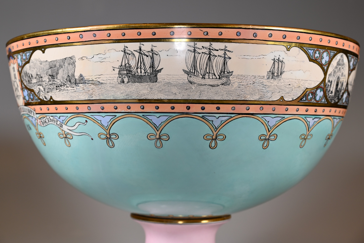 Motiv runt skålens mynning, fr.v: 1. Gotlands landskapsvapen, krönt, med inskription: "AT GOTLANDS NATION AF LANDSMAN I STOCKHOLM 1876". 2. Marinmotiv med tre fartyg, koggar. 3. S:t Nicolai kyrkoruin. 4. Pärkspel. 5. Stenkors, ringkors. 6. Visbysilhuett mot havet med ringmuren.