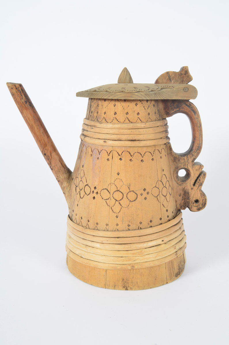 Kanne lagget av åtte staver som smalner opp. Tut og hank i ett med hver sin stav. Nederst seks gjorder og fire øverst. Lokket er buet med kjegleformet topp, ender i nebb og er festet til hanken med trepinne. Hanken nederst har opp-ned slangehode. Sviornamentikk på både kanne og lokk. Lokket er av nyere dato.