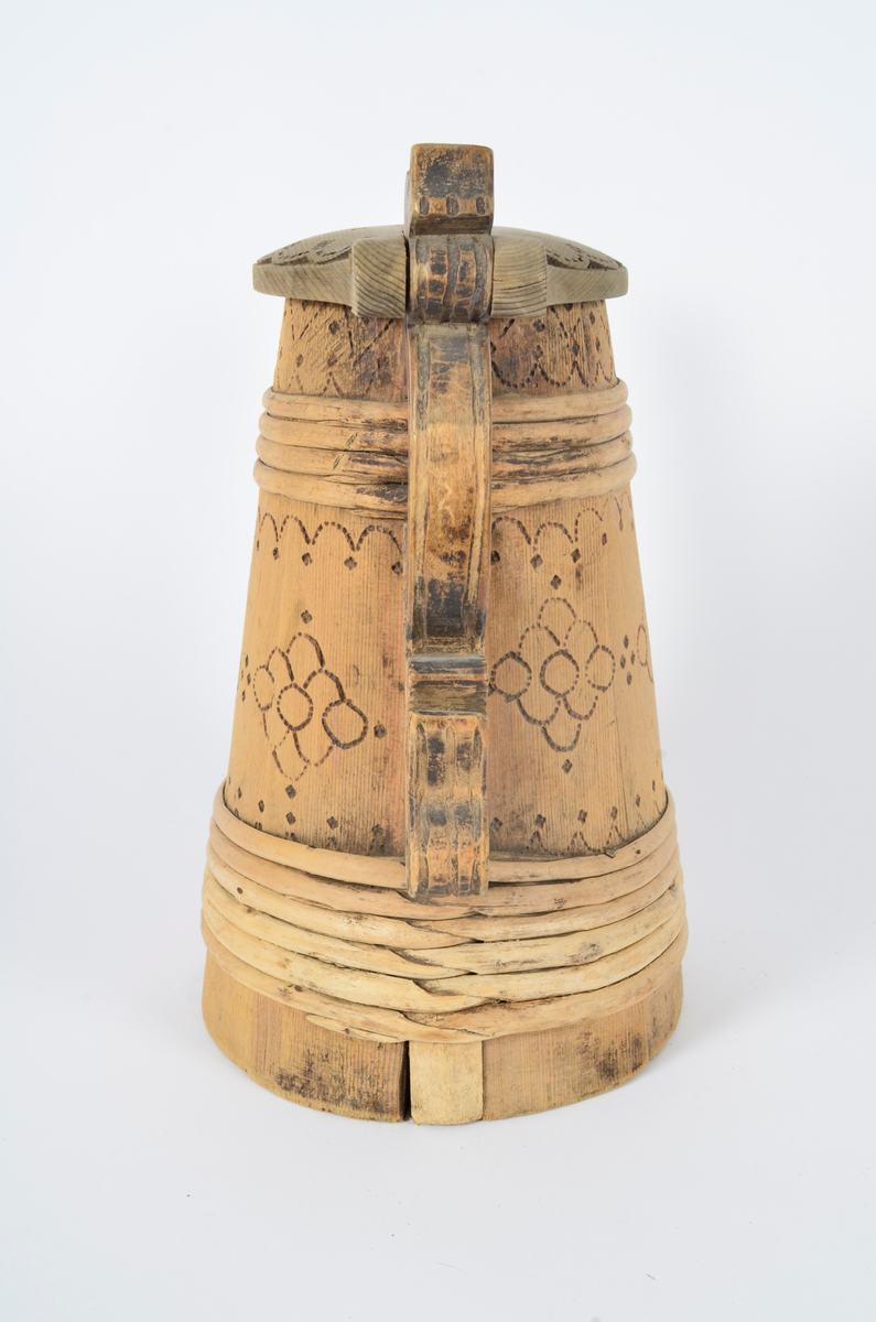 Kanne lagget av åtte staver som smalner opp. Tut og hank i ett med hver sin stav. Nederst seks gjorder og fire øverst. Lokket er buet med kjegleformet topp, ender i nebb og er festet til hanken med trepinne. Hanken nederst har opp-ned slangehode. Sviornamentikk på både kanne og lokk. Lokket er av nyere dato.