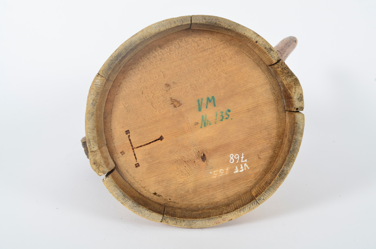 Kanne lagget av åtte staver som smalner opp. Tut og hank i ett med hver sin stav. Nederst seks gjorder og fire øverst. Lokket er buet med kjegleformet topp, ender i nebb og er festet til hanken med trepinne. Hanken nederst har opp-ned slangehode. Sviornamentikk på både kanne og lokk. Lokket er av nyere dato.