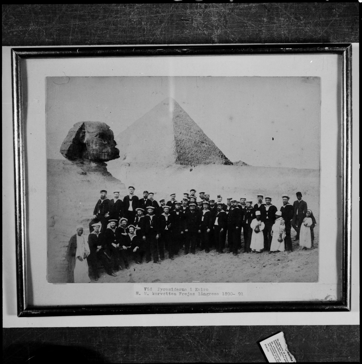 Bilden föreställer korvetten FREJAS besättning som har tagit uppställning framför sfinxen och pyramiderna för en gruppfoto under långresan 1889-90.