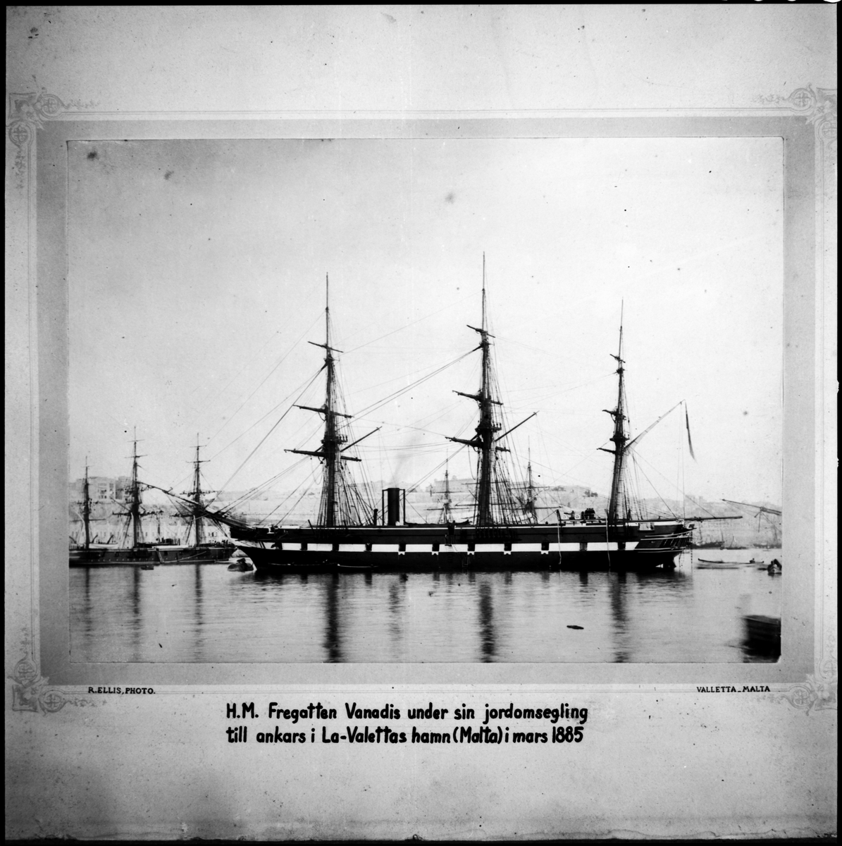 Bilden visar ångfregatten Vanadis från styrbordssida. Skeppet ankra vid en boj i Vallettas hamn på Malta under sin långresa 1883-1885. Alla segel är bärgade, styckportarna är öppna och kanonerna utförda. Ur skorstenen stiger rök. En grupp sjömän står på akterdäcket. Från akterskeppet hänger en repstege ner till vattenytan och flera små båtar verka trafikera från och till fregatten.
I bakgrunden syns Valettas stadsbefästningar och regeringspalatset Auberge de Castille et Léon.