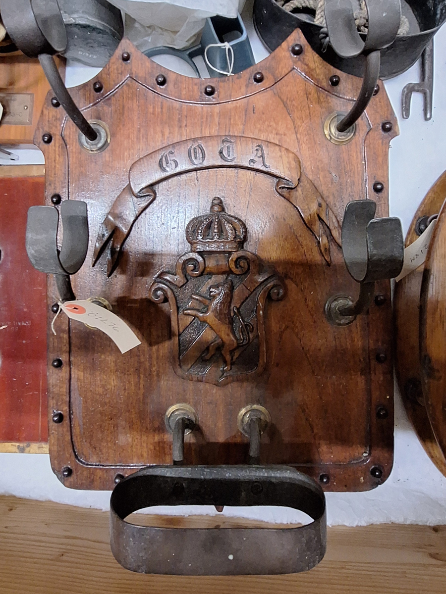 Kikarställ med namnet GÖTA i en bandslinga och Göta vapen i mitten. Hållare för två stycken långkikare. På baksidan stöd för ställets upphängning.