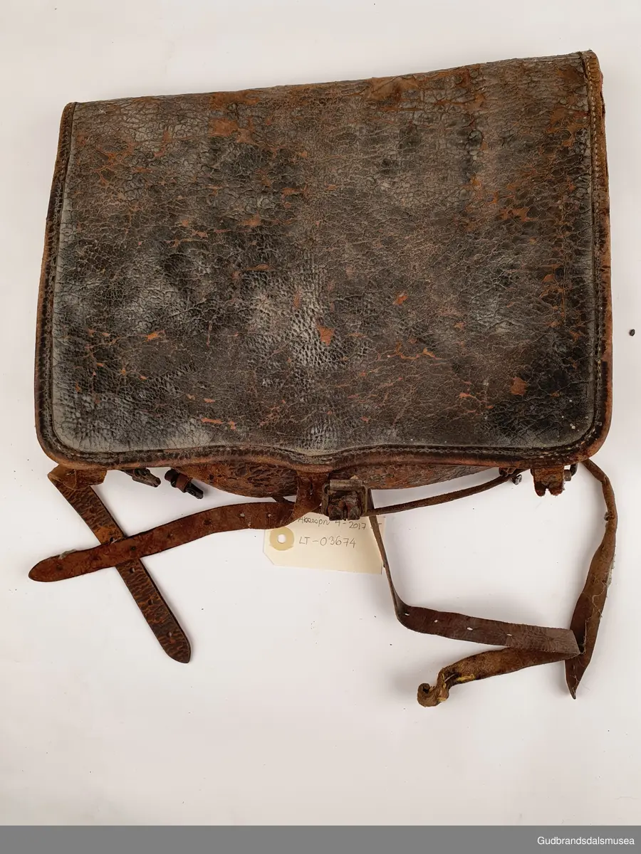 Liten ransel i skinn. Lokk med lukning og skulderreimer for å bære på ryggen.
Er foret med striestoff

Bredde 34cm
Høyde 28 cm
Dybde 8 cm

Teknikk; søm
Matriale ; lær/skinn