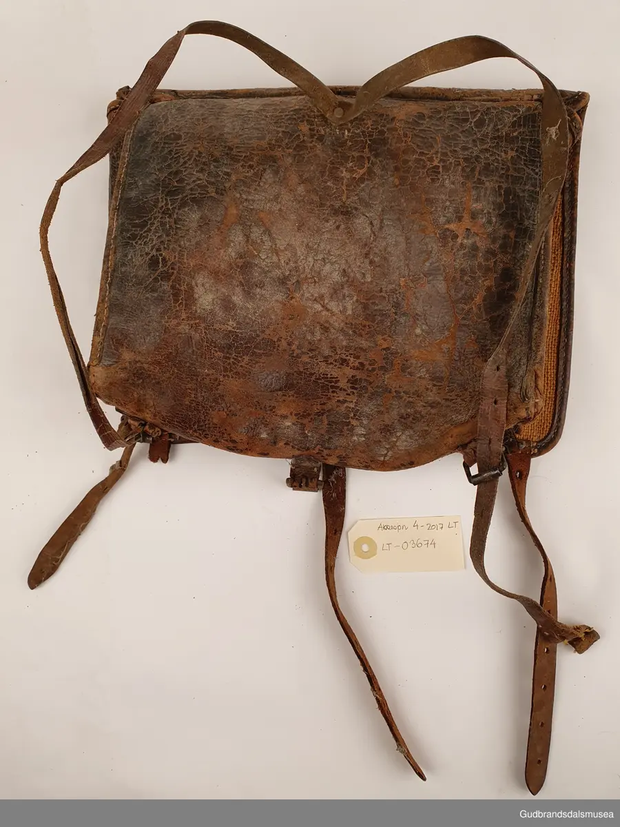Liten ransel i skinn. Lokk med lukning og skulderreimer for å bære på ryggen.
Er foret med striestoff

Bredde 34cm
Høyde 28 cm
Dybde 8 cm

Teknikk; søm
Matriale ; lær/skinn
