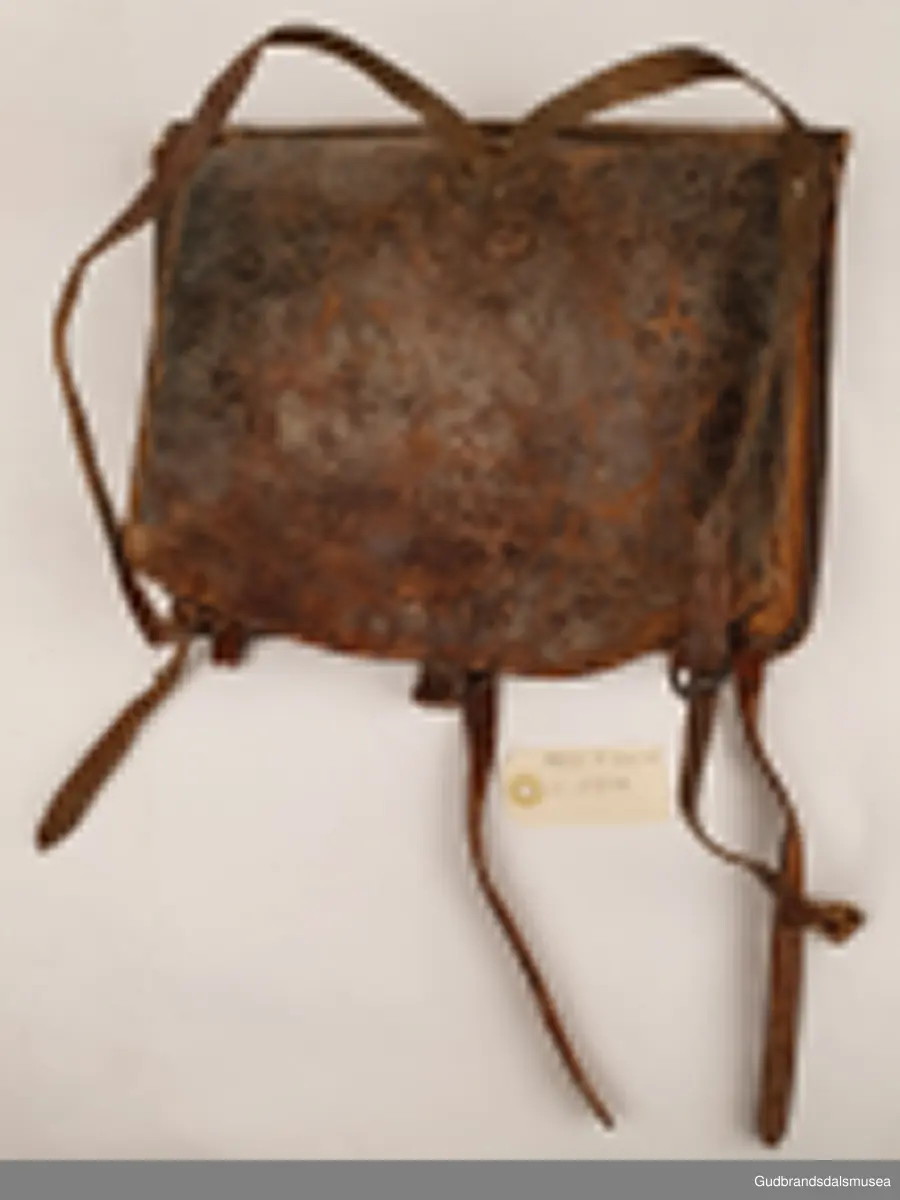 Liten ransel i skinn. Lokk med lukning og skulderreimer for å bære på ryggen.
Er foret med striestoff

Bredde 34cm
Høyde 28 cm
Dybde 8 cm

Teknikk; søm
Matriale ; lær/skinn