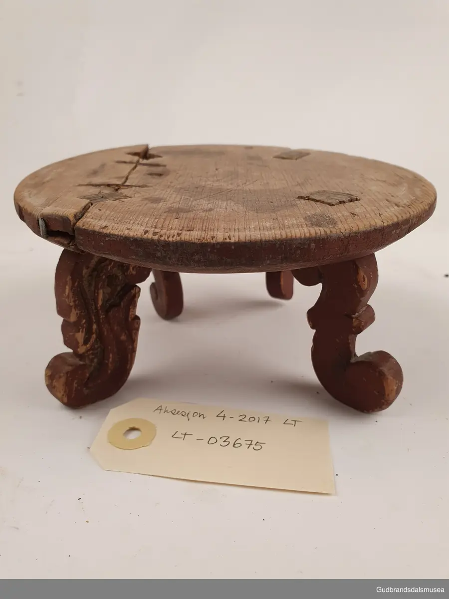 Smørbrikke i tre med 4 føtter. Føttene er ulikt utformet. En reprasjon på platen med kramper.
Merket med svimerke under FNV

Diameter 17 cm
Høyde 8 cm

Matriale; tre
Teknikk; utskjøring, sage, spikke, pusse, dreie