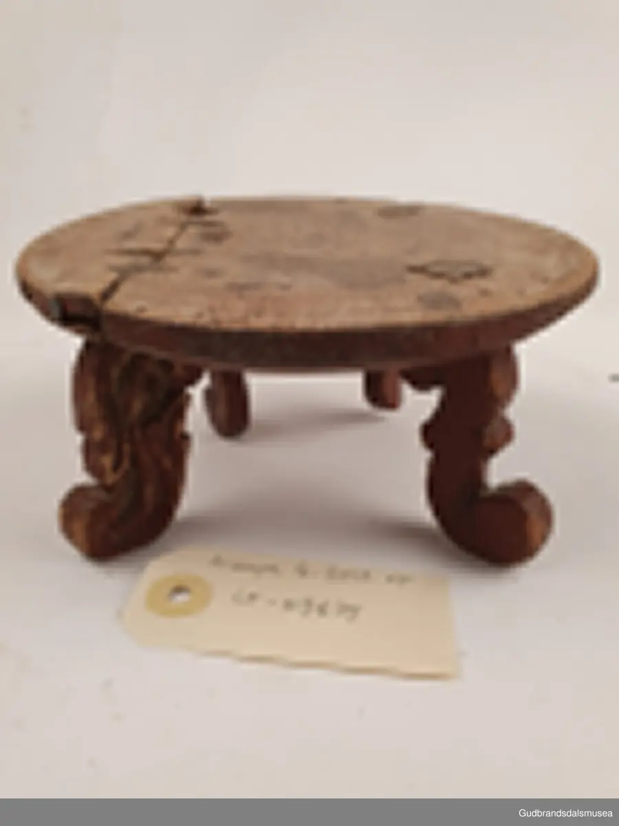 Smørbrikke i tre med 4 føtter. Føttene er ulikt utformet. En reprasjon på platen med kramper.
Merket med svimerke under FNV

Diameter 17 cm
Høyde 8 cm

Matriale; tre
Teknikk; utskjøring, sage, spikke, pusse, dreie