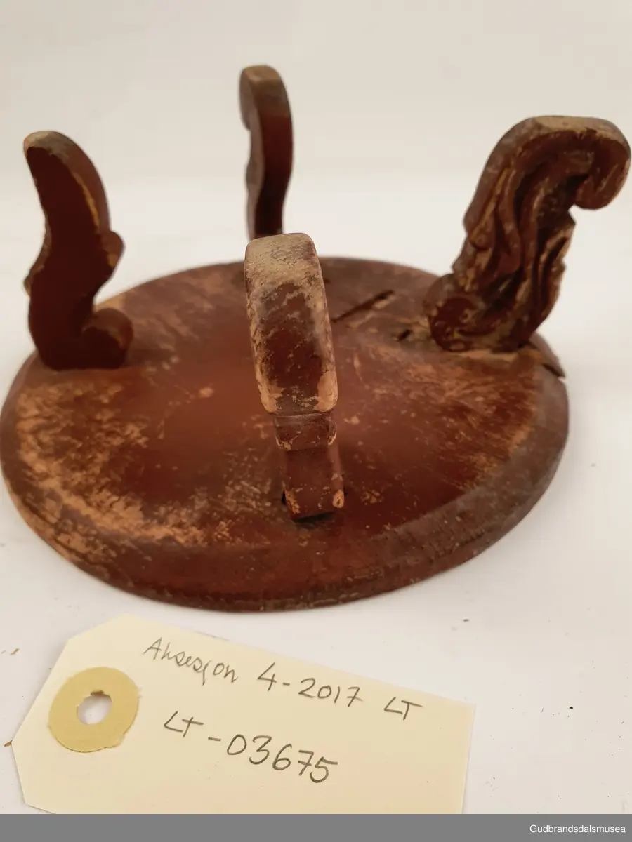 Smørbrikke i tre med 4 føtter. Føttene er ulikt utformet. En reprasjon på platen med kramper.
Merket med svimerke under FNV

Diameter 17 cm
Høyde 8 cm

Matriale; tre
Teknikk; utskjøring, sage, spikke, pusse, dreie