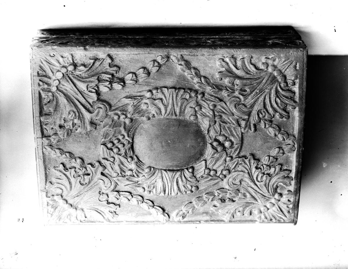 Träskrin med snidat blad- och blommönster i relief.