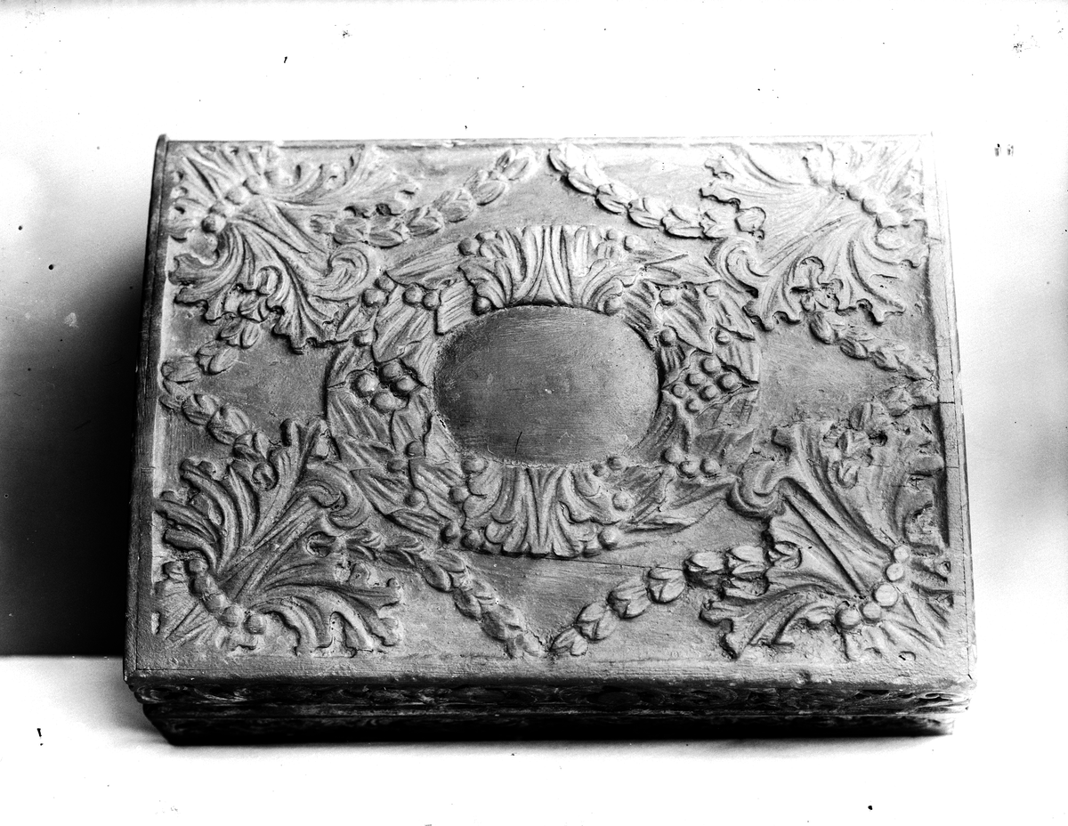 Träskrin med snidat blad- och blommönster i relief.
