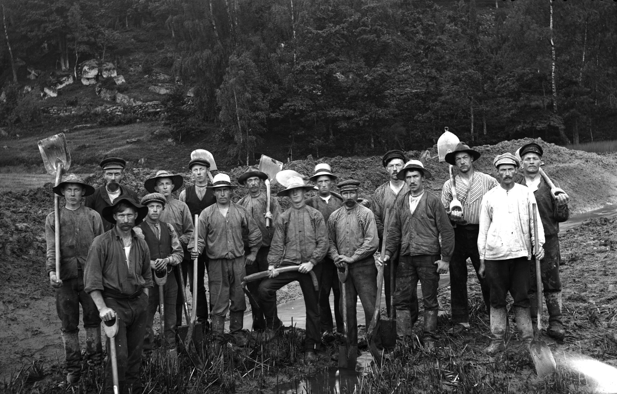 Grävarlag vid ån Skuttran vid gränsen till Grimmared. Man arbetade 10 timmar/dag och dagspengen var 2 kr per dag. (Se även bild GEA051)
Personer: 1) Ivar Johansson, Hulta Veddige, 2) Förmannen från Källsjö, 3) Källsjöbo, 4) fr Stamnared, 5) Johan Johansson, Stora Råryd, Torkels, 6) Klas Johansson, Sällstorp 10, Gers (uppgiftslämnare) 7-8) Källsjöbor, 9) Karl Almer Berntsson, Kusagärde, 10) Källsjöbo, 11) Bernt August Bengtsson, Kusagärde, 12) Birger Gustafsson, Stamnared (Eskillahagen), 13) Källsjöbo, 14) Kungsätersbo, 15) Hjalmar…..Vallby, Veddige (Riskullen, 16) Källsjöbo.