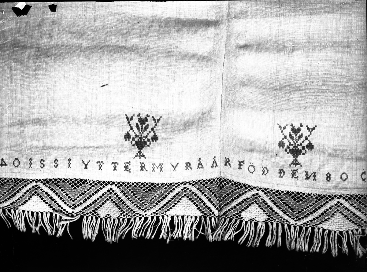 Hänglakan med bård i pinnspets, broderi och märkning i korssöm "...4OISSIYTTERMYRAÄRFÖDDEN8OC...". Ovansjö.