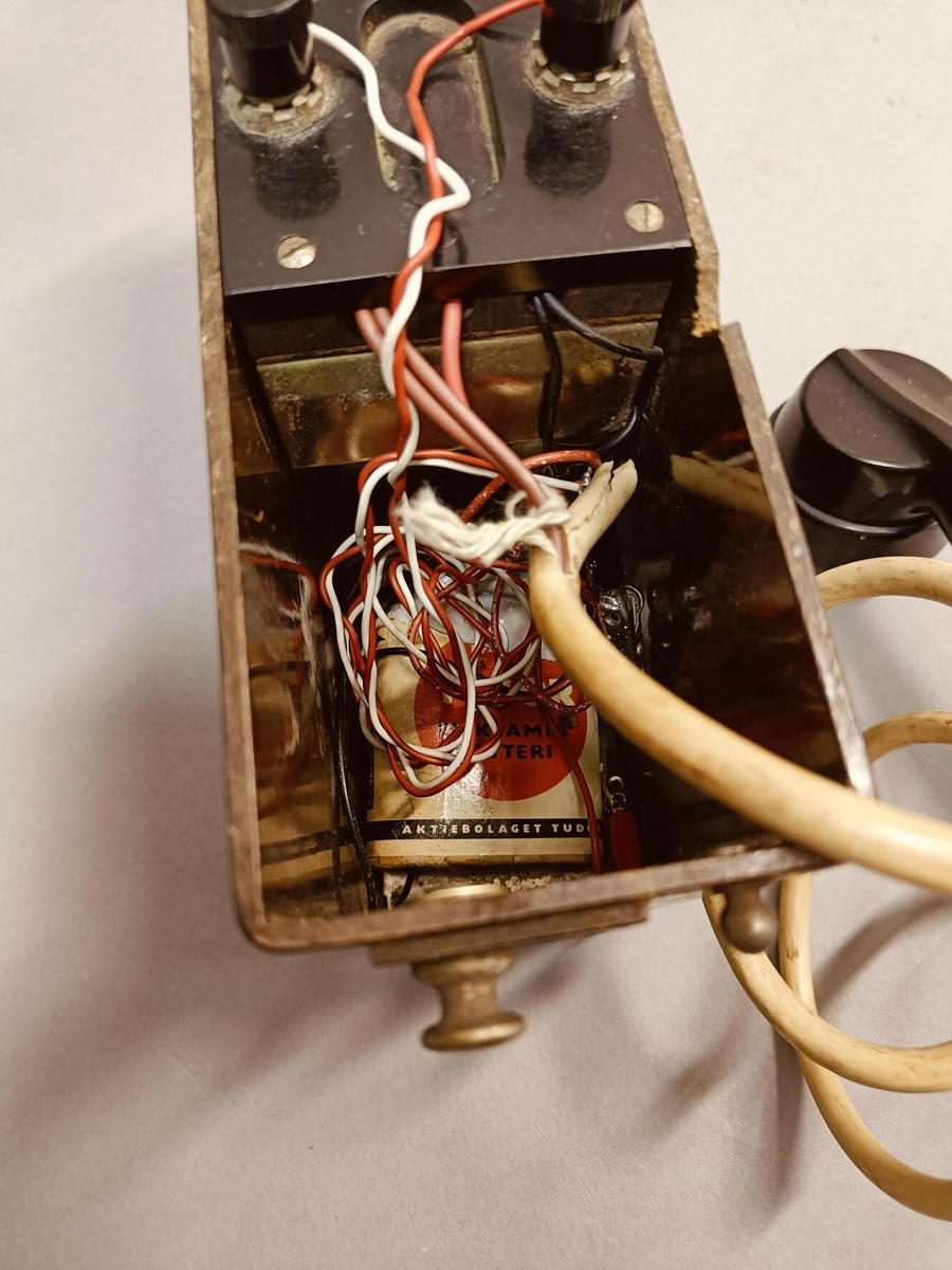 Smal rektangulær boks med lokk og magnetoapparat innvendig.