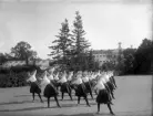 En trupp kvinnliga gymnaster övar i det fria utanför dåv. seminariet, dvs numera Ringsbergsskolan i Växjö.  I bakgrunden syns skolans växthus och dåv. cellfängelset.