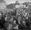 Studenterna andra dagen, 13/5 1958. 
Virrvarr av studenter och gratulanter på Stortorget. 
I bakgrunden syns några av husen längs Kronobergsgatan och byggnads-
ställningar runt domkyrkans torn.