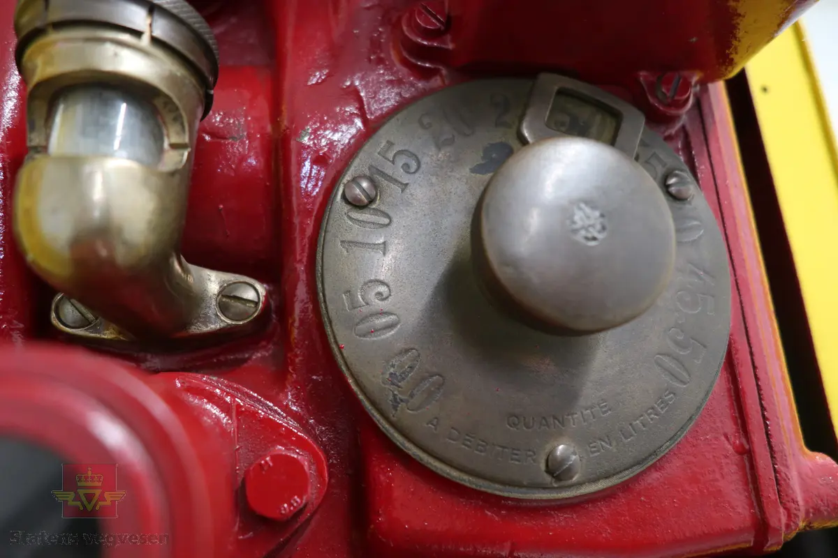 Manuell bensinpumpe, sylinderformet, med to dører som kan åpnes. Gul og rød med Shell logo utvendig, rød innvendig med teksten SHELL på dørene. Påskrudd Shell-logo på toppen av pumpa. Innmaten består av to 5-liters måleglass, telleverk, håndpumpe og slange med pumpepistol. Telleverket for en enkel fylling går til 50 liter. Ifølge telleverket ser det ut som det er fylt snaut 7000 liter fra pumpa. Pumpa har merking fra HARDOLL.
Pumpa er pusset opp.