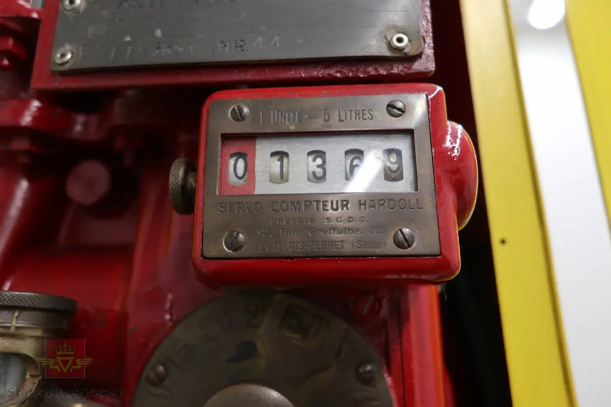 Manuell bensinpumpe, sylinderformet, med to dører som kan åpnes. Gul og rød med Shell logo utvendig, rød innvendig med teksten SHELL på dørene. Påskrudd Shell-logo på toppen av pumpa. Innmaten består av to 5-liters måleglass, telleverk, håndpumpe og slange med pumpepistol. Telleverket for en enkel fylling går til 50 liter. Ifølge telleverket ser det ut som det er fylt snaut 7000 liter fra pumpa. Pumpa har merking fra HARDOLL.
Pumpa er pusset opp.