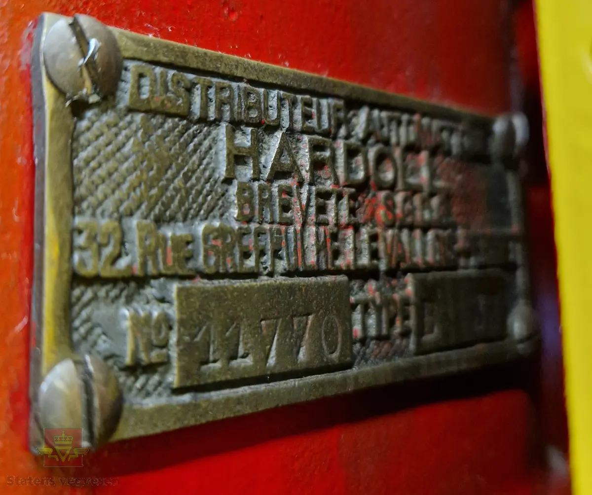 Manuell bensinpumpe, sylinderformet, med to dører som kan åpnes. Gul og rød med Shell logo utvendig, rød innvendig med teksten SHELL på dørene. Påskrudd Shell-logo på toppen av pumpa. Innmaten består av to 5-liters måleglass, telleverk, håndpumpe og slange med pumpepistol. Telleverket for en enkel fylling går til 50 liter. Ifølge telleverket ser det ut som det er fylt snaut 7000 liter fra pumpa. Pumpa har merking fra HARDOLL.
Pumpa er pusset opp.