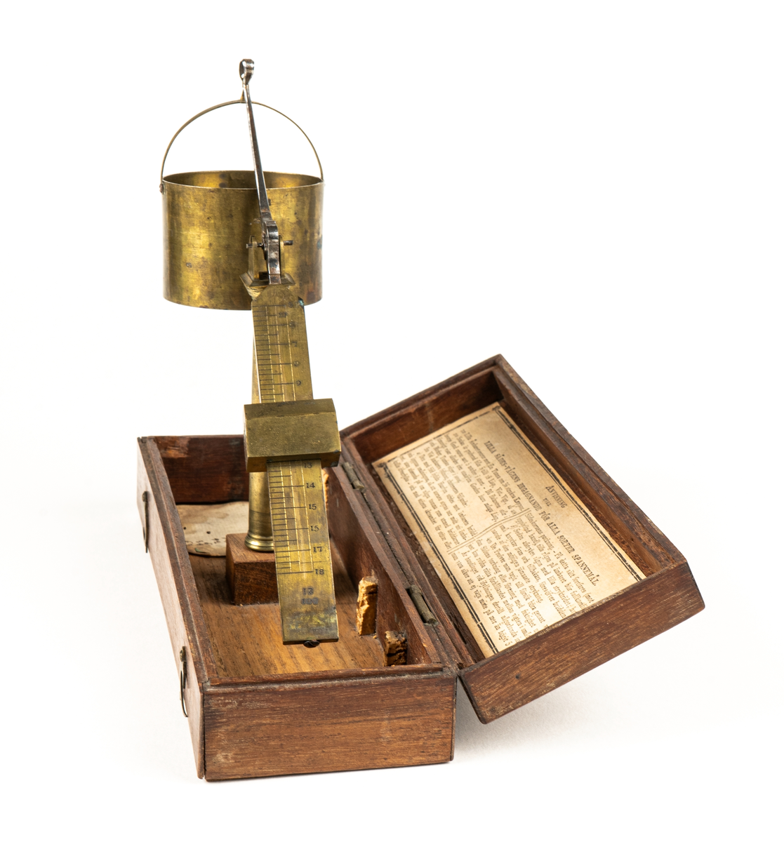 Våg av mässing, för uträkning av spannmålsvikt. Liten provvåg i fodral av trä. Måtten anger fodralets mått.