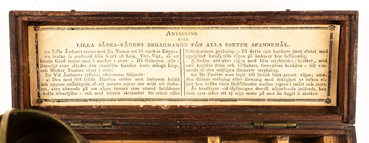 Våg av mässing, för uträkning av spannmålsvikt. Liten provvåg i fodral av trä. Måtten anger fodralets mått.