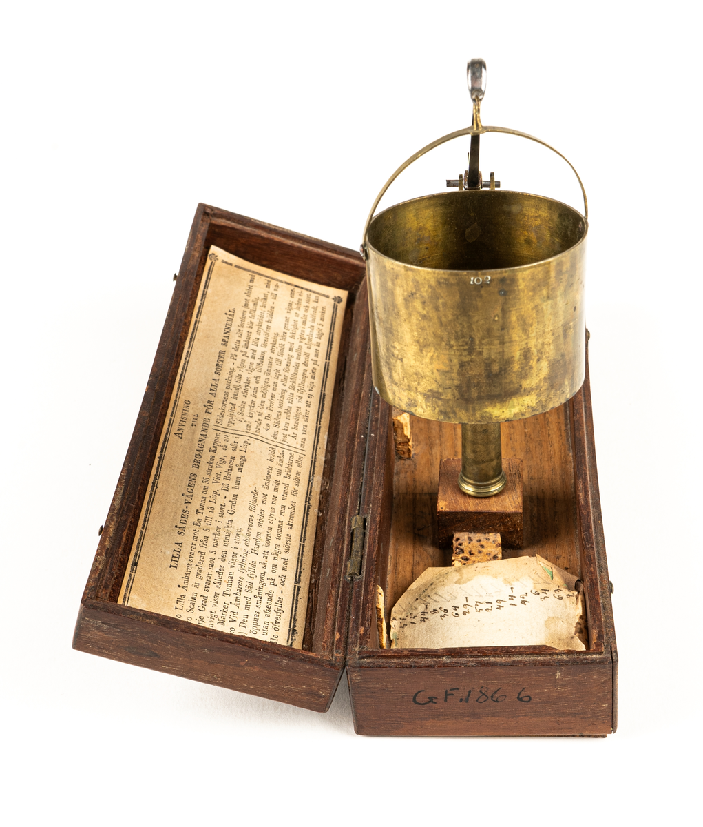 Våg av mässing, för uträkning av spannmålsvikt. Liten provvåg i fodral av trä. Måtten anger fodralets mått.