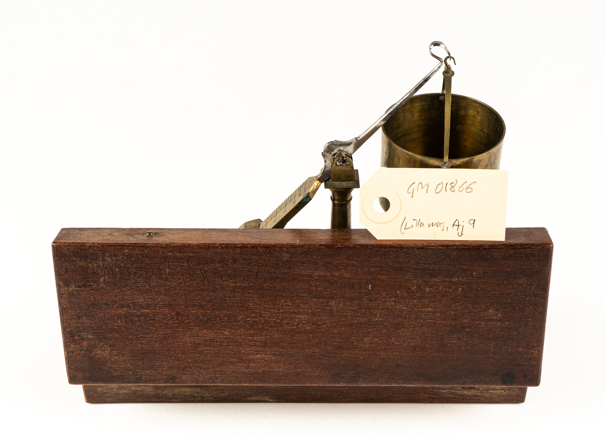 Våg av mässing, för uträkning av spannmålsvikt. Liten provvåg i fodral av trä. Måtten anger fodralets mått.