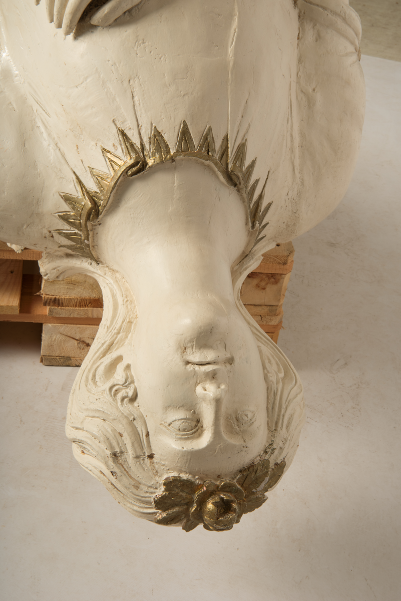 Helfigur, dame med gullrose i håret. Hvit kjole med gullkant, mørkt hår, blå sokkel med rødt emblem