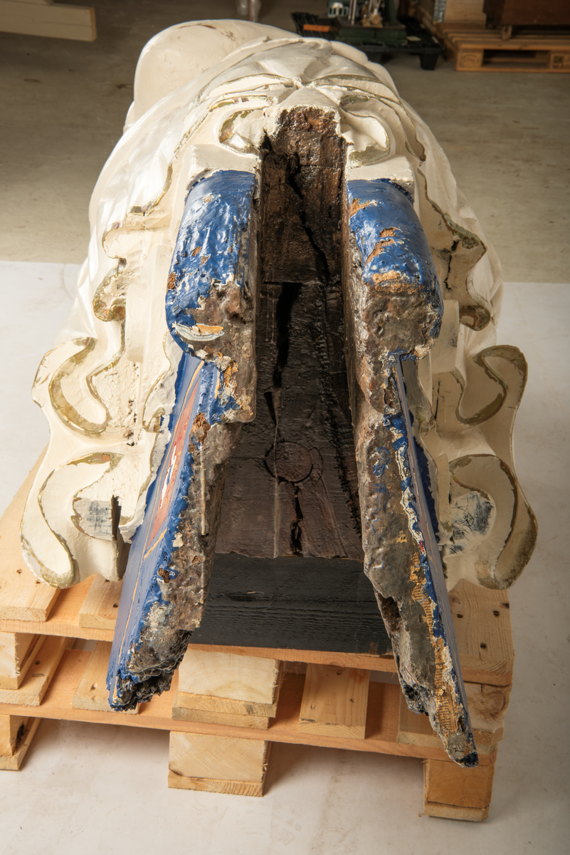 Helfigur, dame med gullrose i håret. Hvit kjole med gullkant, mørkt hår, blå sokkel med rødt emblem