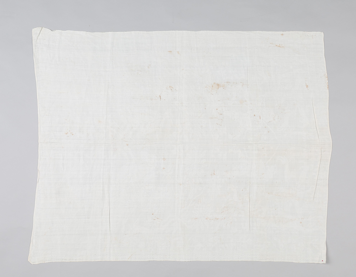 Hvit lindamask med mønster: damer til hest med jaktfalk, hornblåsende jegere med hunder, blomstermønster samt enkeltbord på langsidene. Smal fall på kortsidene. Merket med liten rød stjerne.