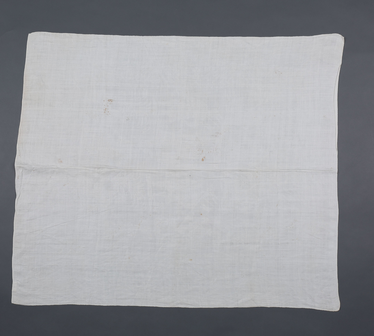 Hvit lindamask med sjakkbrett-bord langs alle fire sider. Og bred bord innenfor med trofèoppstillinger. I hvert hjørne en figur med allongeparykk. På midtpartiet en sittende og en ståendefigur ved siden, og øverst stående figur med stor hatt og tregruppe. Mønster fra beg. av 1700. Serviettene har smal fall på kortsidene.