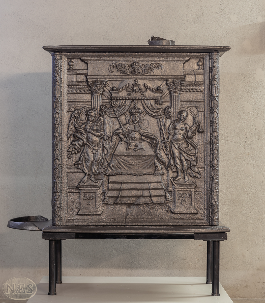 En rektangulær kasseovn med åpning på kortsiden. På langsiden - gjengivelse av tittelbladet til Christian V sin norske lov. På arkitraven over tronstolen C 6 i kronet speilmonogram mellom palmegrener. På de allegoriske figurenes (Overflødighetsgudinnen og Justitia) postamenter Christian VI sitt valgspråk. Faste skinner med geometrisk ornamentikk.
Øverst på kortsiden de forenede rikers våpen omgitt av elefantordens kjede. Nederst påskrift omgitt i en kartusj.