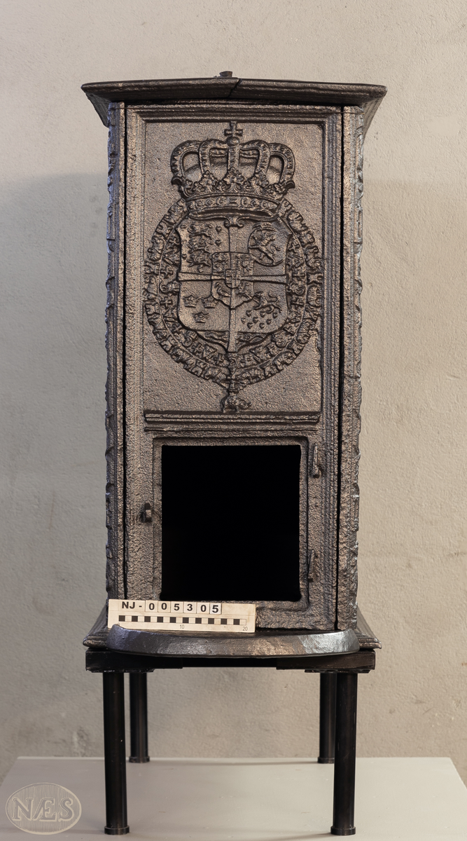 En rektangulær kasseovn med åpning på kortsiden. På langsiden - gjengivelse av tittelbladet til Christian V sin norske lov. På arkitraven over tronstolen C 6 i kronet speilmonogram mellom palmegrener. På de allegoriske figurenes (Overflødighetsgudinnen og Justitia) postamenter Christian VI sitt valgspråk. Faste skinner med geometrisk ornamentikk.
Øverst på kortsiden de forenede rikers våpen omgitt av elefantordens kjede. Nederst påskrift omgitt i en kartusj.