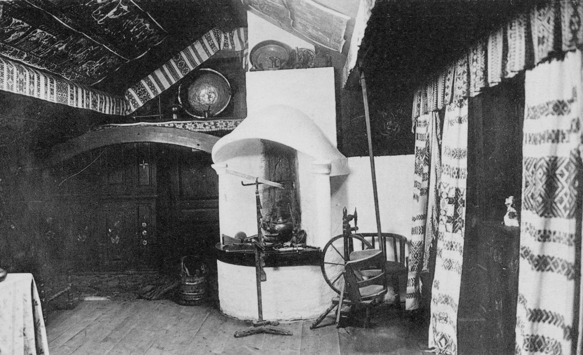 2 st Vykort från "Hallands museums Ryggåsstuga å Tivoli, Halmstad." Bild 1: Interiör med dukat bord i "dragen stuga", dvs med bonader och textilier på väggar och tak. Bild 2: Interiör med öppen spis och textilier.
