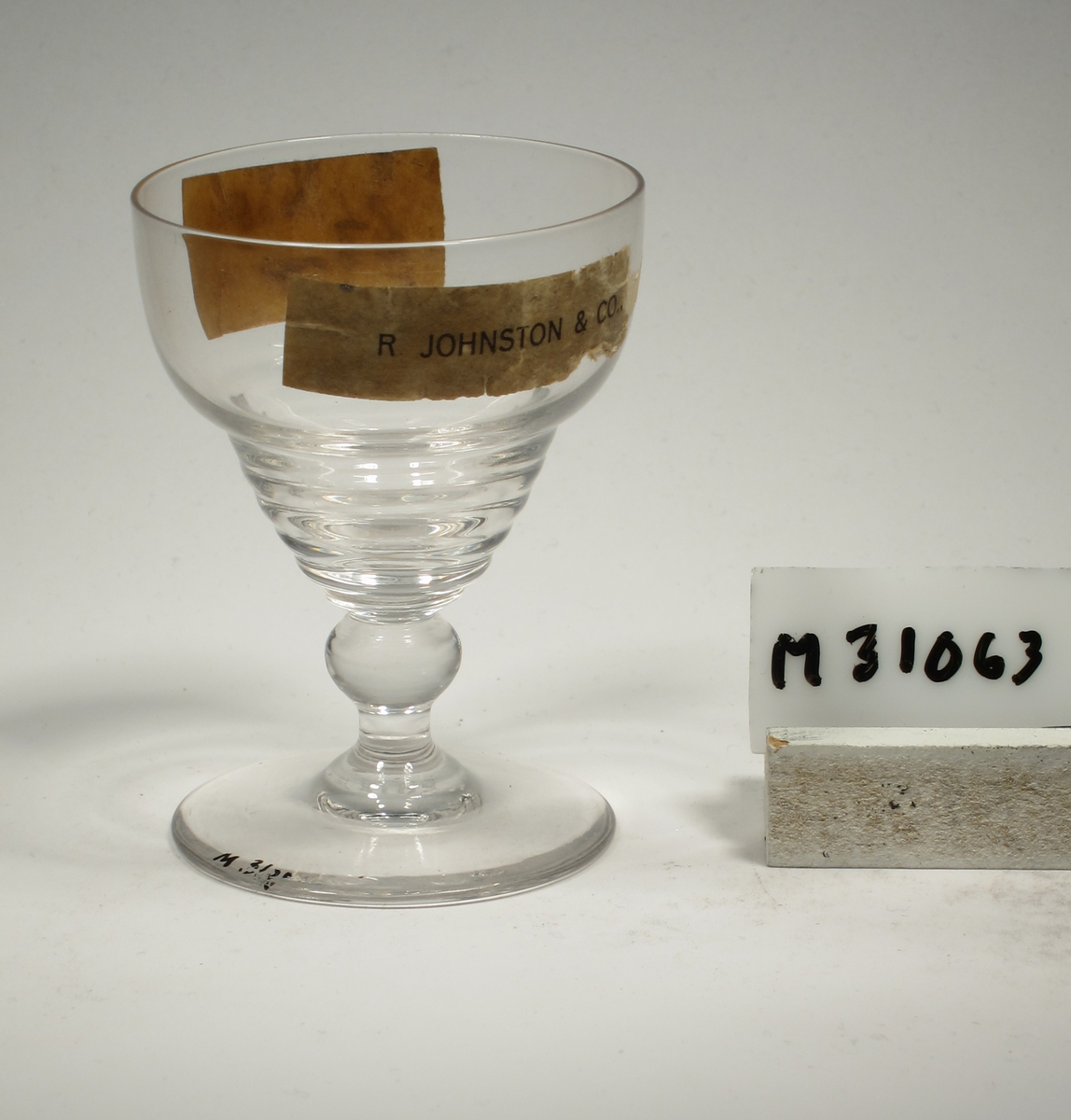 Formgivare: Ingrid Atterberg. Portvinsglas på ben och fot. Ovoid kupa med horisontella vulster på nedre delen. Pelarben.