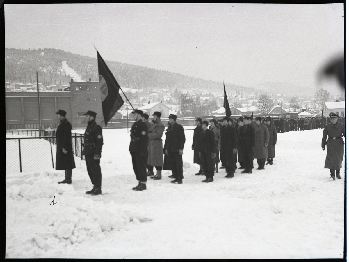 Foto av Hirden på samarbeidende øvelse med Wehrmacht. Tysk offiser kan ses gående på høyre side i bildet. 

Foto tatt ved Marienlyst, i bakgrunnen kan man se "Turnhallen" 

Påskrift på konvolutt: 
NS 2/2 1941 - Drammen
21 - 30