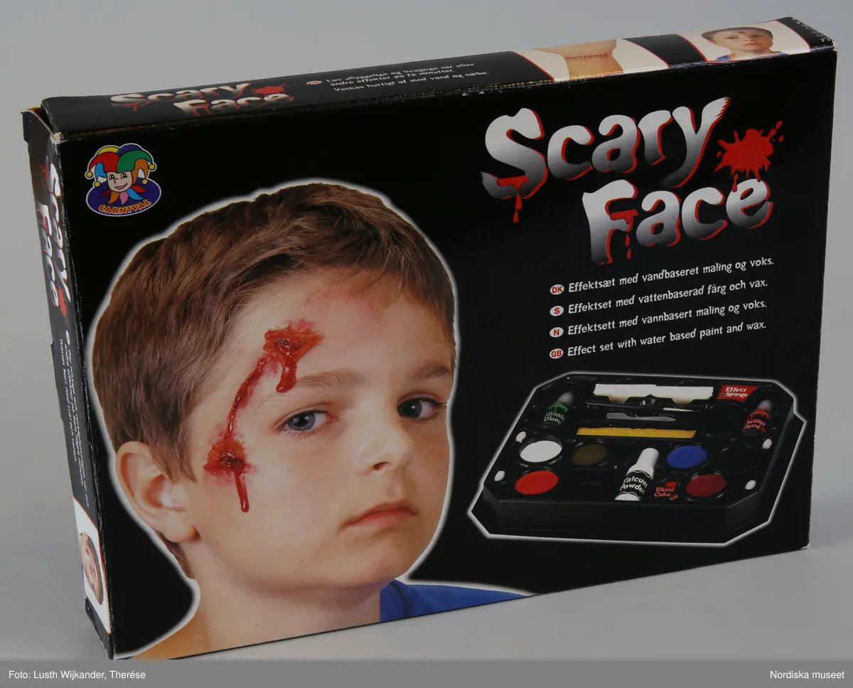 Katalogkort:
"Sminkset, halloweensminkset. maskeradsminkset 'Scary Face' i svart platsrelieflåda med tillhörande förvaringskartong i papp och introduktionsskrift i svart bottenfärg. Innehåller färger, teaterblod, monsterblod, blodsalva, vax, sminkborstar, pensel. talk svampar och spatel. Har använts i samband med Halloweenfirande. Födelsedagspresent till Andreas son Marvin år 2000. Ingår i Antikvariska avdelningens halloweendokumentation 2002, bestående av foton, intervjuer och deltagande observation. Sminksetet är ofullständigt efter användning. Lena Kättström Höök, Anna Asplund 2002."