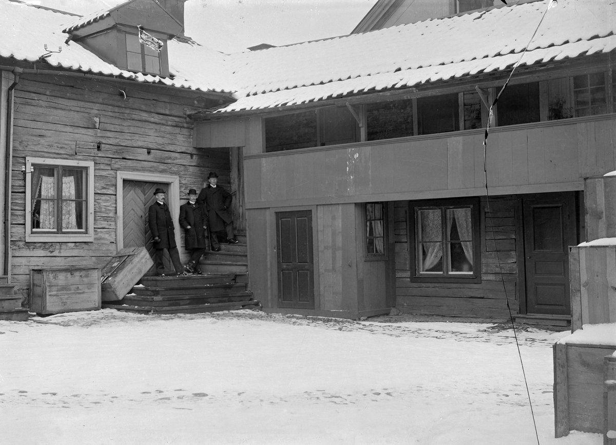 Granbomska gården kallade samtiden fastigheten Storgatan 54 i Linköping. Uppkallad efter handlarfamiljen som från mitten av 1800-talet drev artikelbutik från platsen. I samtid med bilden upplyser tidningen Östgöten hösten 1896 att man flyttat rörelsen till gatuhuset väster om bildens hörn mot Apotekaregatan. Det något anonyma huset kvarstår in i vår tid -granne med Stenhusgården- men med en förenklad fasad. Den som då stod på Storgatan såg firmans huvudsakliga inriktning i texten "Glas, Porslin och Lampaffär". Av vad som lediggjordes med flytten, och i övrigt rymdes, räknar nämnda tidningsartikel upp en förvånansvärd mängd verksamheter i gården; Pianifabriken C G Söderbergs Eftr, Webers ångbageris filial, Lina Hallbergs cigarrhandel, Maria Åbergs blomsterhandel och en skohandel samt en ölkrog. Männen på trappan är oss okända men någon Granbom är trolig. Defekt.