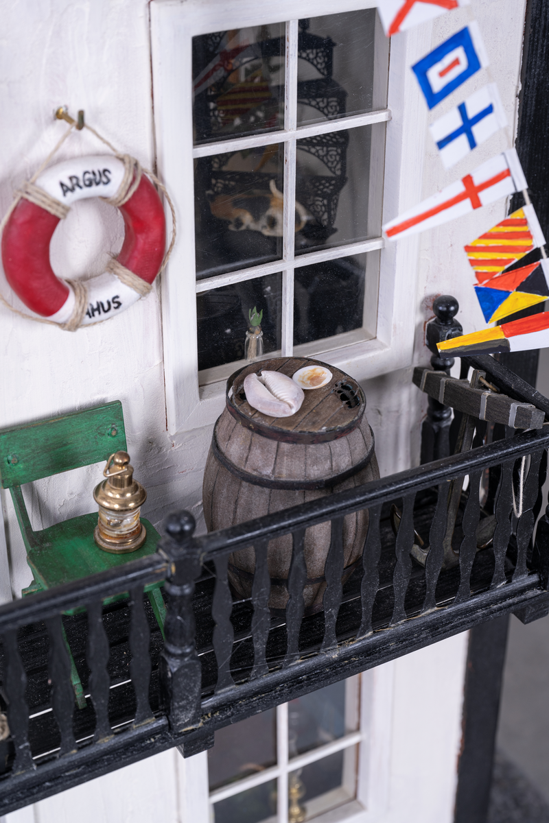 Stort miniatyrhus med sju inredda rum. Totalt ca 1300 inredningsdetaljer, från möbler till husgeråd. Speglar ett hus vid havet, ett sjöofficershem under 1900-talet.