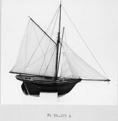 Båtmodell av segelkuttern HELMI, byggd i ett stycke med däcksinredning oc överhängande stäv. Akterspegel med hackbräde. Roder med rorkult av järn. Riggad, mast med stång, gaffelsegel, fock och klyvare. Svartmålad, förgylld list, grön vattengång. Fernissat däck. Tillhörande monter: svart.