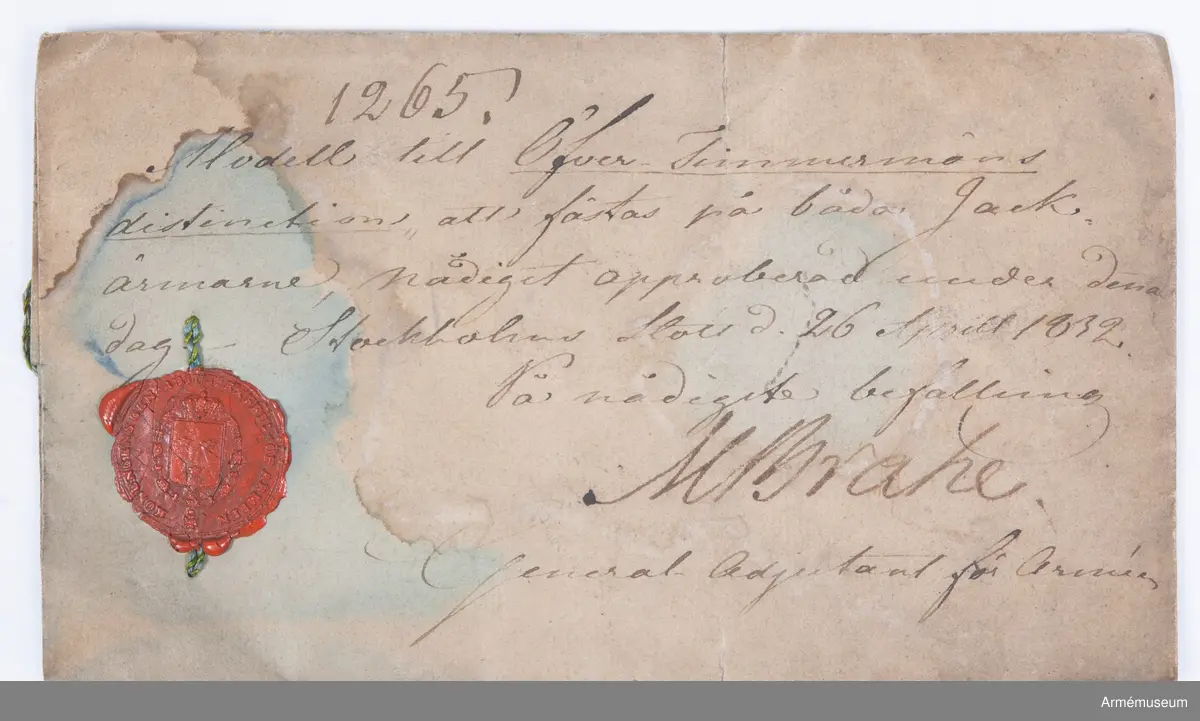 Två distinktionstecken av mässing i form av två korslagda yxor. Tecknen har 8 hål för fastsättning på uniformen.
Tecknen är fastsydda på fracken AM.015502:s ärmar.

Till distinktionstecknen hör en modelletikett med rött vaxsigill och följande text:
"Modell till Öfver-Timmermans distinction, att fästas på båda Jack ärmarne, Nådigast approberad under dena dag, Stockholms Slott d. 26 Aprill 1832, På nådigaste befallning M. Brahe, General Adjutant för Armén".
Sigillet pryds av Lilla Riksvapnet i mitten med följande text runt om: "Konungens Gen. Adjuts. Exprd. för Arméen".